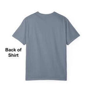 May include: Back view of a plain blue-grey t-shirt. The short-sleeved shirt has a crew neck and is made of a soft material. The text "Back of Shirt" is visible in the lower left corner.
