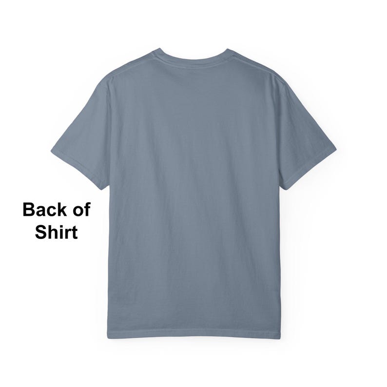 May include: Back view of a plain blue-grey t-shirt. The short-sleeved shirt has a crew neck and is made of a soft material. The text "Back of Shirt" is visible in the lower left corner.