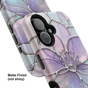 May include: A phone case with a matte finish, displaying a floral pattern in purple, pink, and silver. The design resembles stained glass, with a detailed flower. The text "Matte Finish (not shiny)" is present on the case.