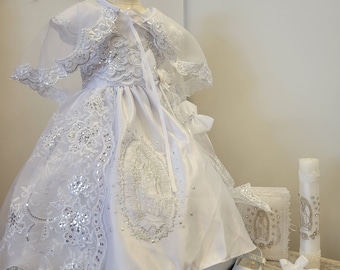 May include: White christening gown with lace and sequins, a matching cape, white shoes, a white candle, a white prayer book, and a white handkerchief.