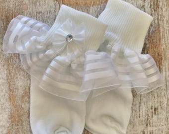 May include: White socks with a white tulle ruffle and a white flower with a rhinestone center.
