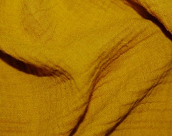 Puede incluir: Tela de color amarillo mostaza con una apariencia texturizada y arrugada. La tela tiene una caída suave y fluida, con pliegues visibles y sutiles variaciones de color. La apariencia general es de un material ligero, posiblemente lino o algodón.