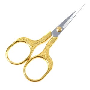 May include: Gold-colored small scissors with a decorative pattern on the handles. The blades are sharp and pointed.