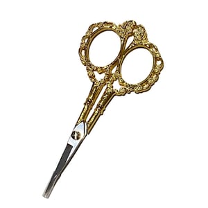May include: Gold-colored decorative scissors with ornate floral designs on the handles. The blades are made of stainless steel.