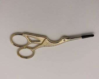 Piccole forbici a forma di cicogna dorata