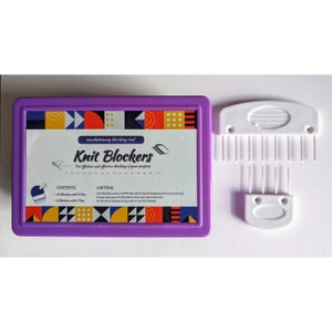 Può includere: Una scatola di plastica viola con uno strumento per ferri da maglia in plastica bianca all'interno. La scatola ha le parole "Knit Blockers" e "revolutionary blocking tool" stampate su di essa. La scatola contiene anche un elenco di contenuti: "12 Blockers with 8 Pins", "8 Blockers with 4 Pins" e "8 Blockers with 4 Pins".