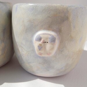 May include: A set of three ceramic mugs with a speckled, matte finish. Each mug features a different color: light blue, cream, and gray. The mugs have a simple, modern design and a comfortable handle.