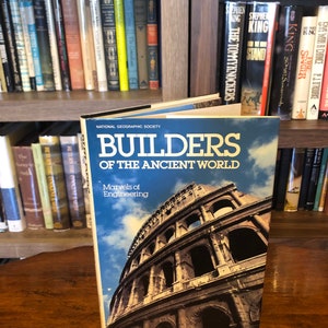 Puede incluir: Un libro de tapa dura titulado "Builders of the Ancient World: Marvels of Engineering" de la National Geographic Society. La portada presenta una fotografía del Coliseo en Roma, Italia.