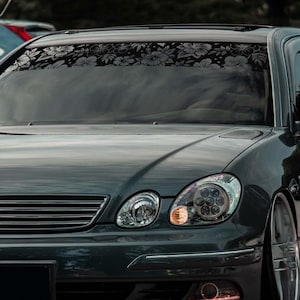 May include: A dark grey sedan with custom modifications, including a lowered suspension and aftermarket wheels. The car has a sleek, modern design with a blacked-out front grille and tinted windows. The car is parked on an asphalt surface.