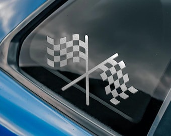 May include: A blue car with a chequered flag sticker on the rear window. The sticker is silver and features two flags crossed over each other. There is a black and white sticker on the side of the car that says "Bad Investments Auto 2016".