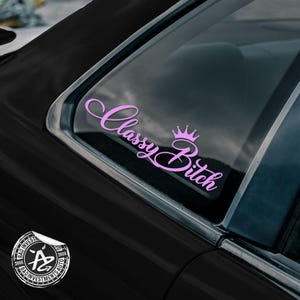 May include: A pink vinyl sticker with the text "Classy Bitch" in cursive lettering with a crown above the word "Bitch".