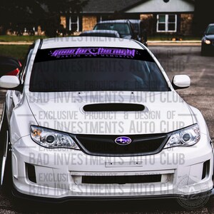 May include: A white Subaru with a black front grille and a purple and black windshield banner that reads "Gone for the Night Making New Memories".