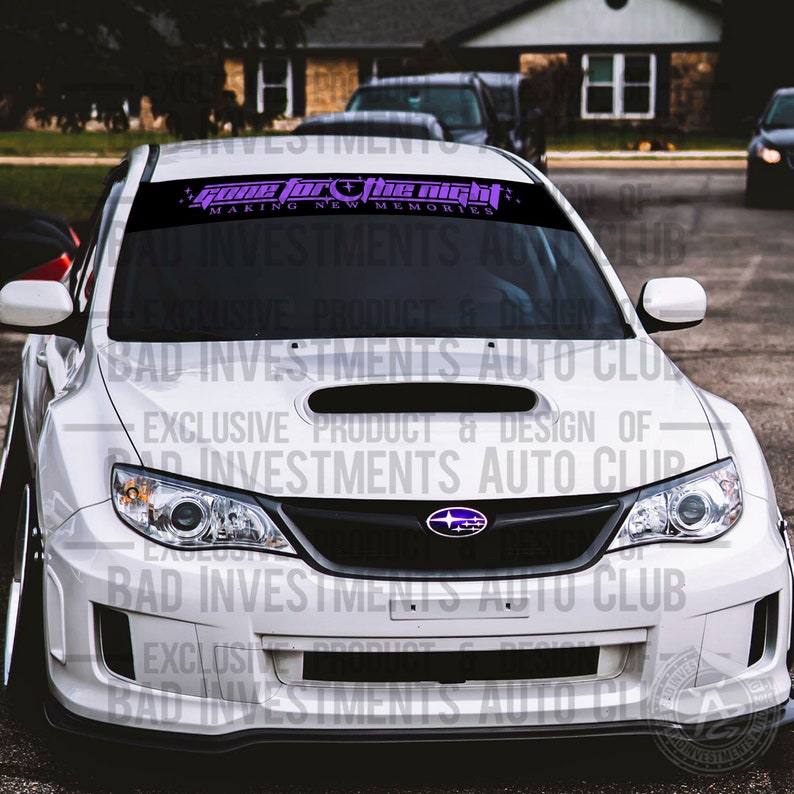 May include: A white Subaru with a black front grille and a purple and black windshield banner that reads "Gone for the Night Making New Memories".