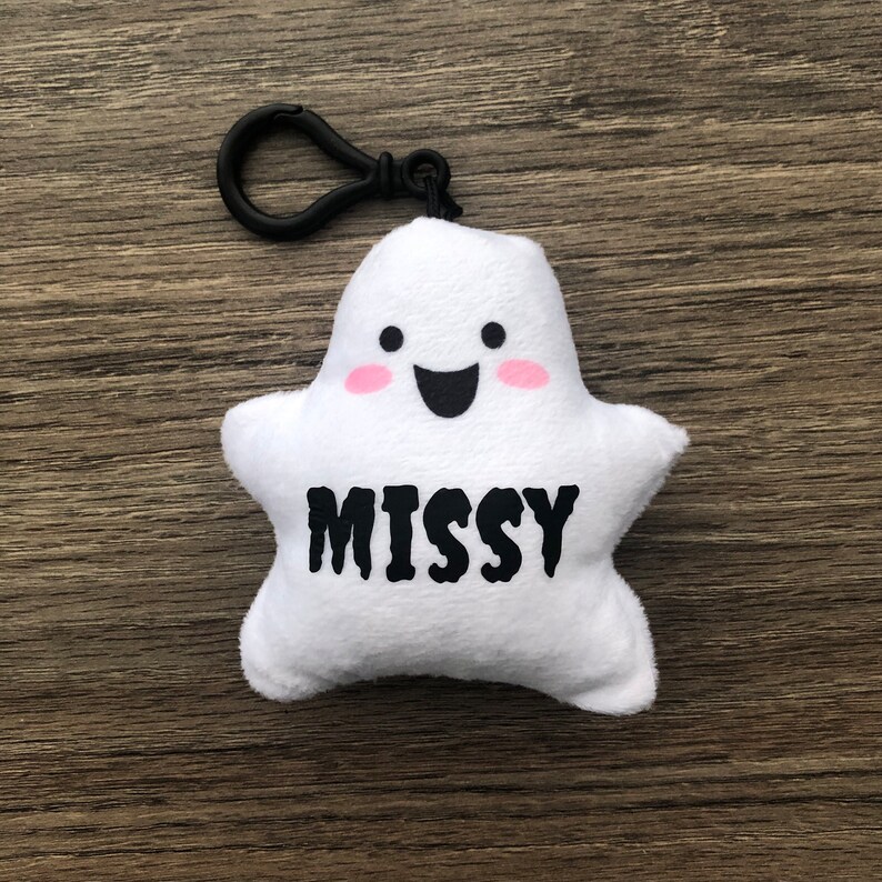 May include: White plush ghost keychain with a black clip, pink cheeks, a smiling face, and the name "MISSY" in black text.