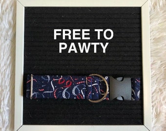 Puede incluir: Un collar para perros azul marino con un estampado festivo de serpentinas y estrellas rojas y blancas. El collar tiene una hebilla de plástico negro y una anilla en D de metal plateado. El texto "FREE TO PAWTY" se muestra en blanco.