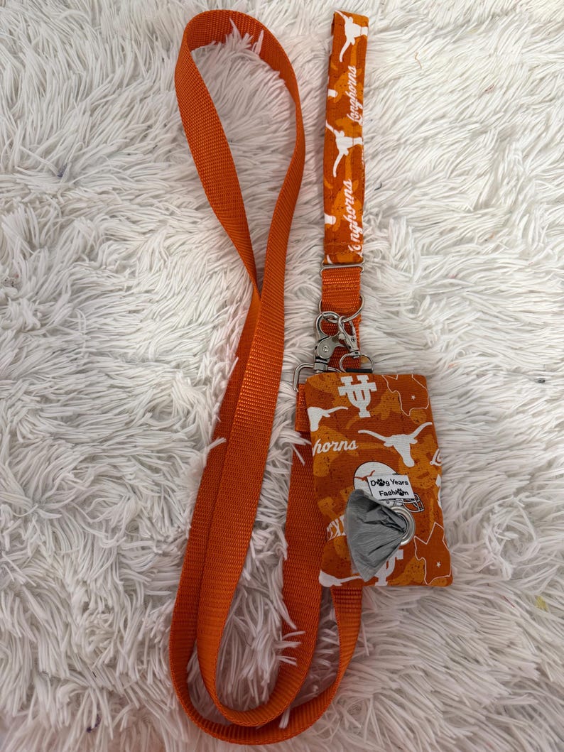 May include: Orange lanyard and matching dog waste bag holder. The lanyard features the text "Longhorns" and a Longhorn logo. The dog waste bag holder has a Longhorn logo and the text "Dog Years Fashion".