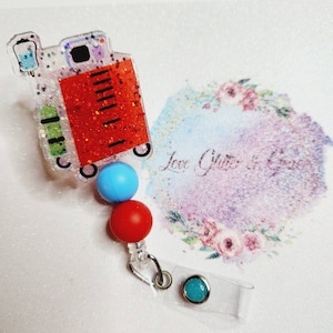 May include: A red and white glitter resin medical bag charm with a blue, red, and turquoise bead lanyard and a clear badge holder with a turquoise bead.