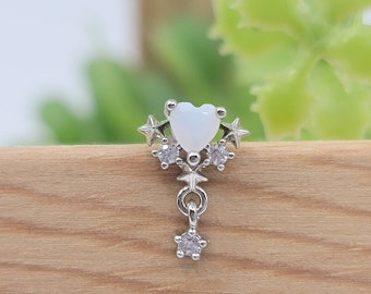 May include: A silver charm with a white heart-shaped stone and star accents. The charm hangs from a silver chain with a small star at the bottom.