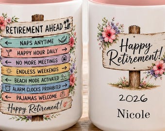 May include: Two white ceramic mugs with light pink interiors and handles. One mug features a wooden signpost graphic with text including Retirement Ahead, Naps Anytime, and Happy Retirement. The other mug displays Happy Retirement, 2026, and Nicole.