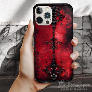 May include: Red phone case with a black ornate design. The case has a distressed look and the design is reminiscent of a gothic style.