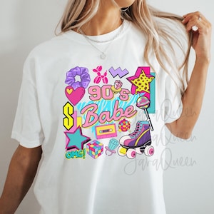 Op de afbeelding: Wit T-shirt met een kleurrijke 90's Babe-afbeelding. Het ontwerp bevat een hart, ster, rolschaats en andere retro-elementen in roze, geel, paars en teal. De tekst "OMG!" is ook inbegrepen.