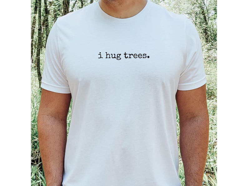 以下が含まれることがあります： 黒い文字で「i hug trees.」とプリントされた白いTシャツ