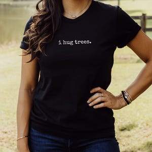 May include: A black t-shirt with the text "i hug trees." printed in white on the front.