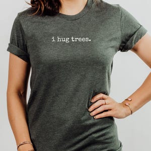 May include: A dark green t-shirt with the text "i hug trees." printed in white on the front.