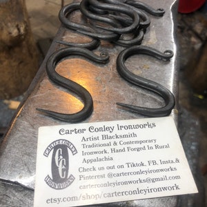 May include: A business card for Carter Conley Ironworks, an artist blacksmith who creates traditional and contemporary ironwork, hand forged in rural Appalachia. The card includes contact information for TikTok, Facebook, Instagram, and email. The card also includes a link to their Etsy shop.