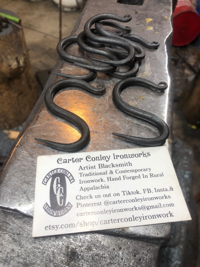 May include: A business card for Carter Conley Ironworks, an artist blacksmith who creates traditional and contemporary ironwork, hand forged in rural Appalachia. The card includes contact information for TikTok, Facebook, Instagram, and email. The card also includes a link to their Etsy shop.