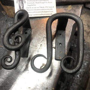 May include: Three black metal hooks with a decorative swirl design. The hooks are hand forged in rural Appalachia. Carter Conley Ironworks is a traditional and contemporary blacksmith.