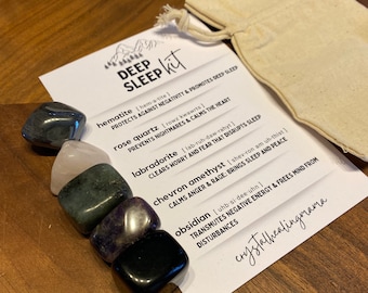 Puede incluir: Un kit de Sueño Profundo con seis piedras preciosas pulidas, incluyendo hematita y cuarzo rosa, junto con una pequeña bolsa de lona. Una tarjeta enumera las propiedades de las piedras. El texto en la tarjeta dice "DEEP SLEEP kit".