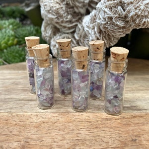 May include: Seven small glass bottles with cork stoppers filled with purple and blue crystal chips.