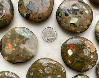 May include: A collection of polished green, brown, and white ocean jasper stones. The stones are smooth and have a variety of patterns and colors.