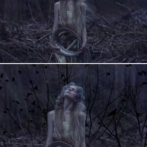 May include: A woman with long blonde hair wearing a white dress and a flower crown holds a silver circular mirror in a dark forest setting.