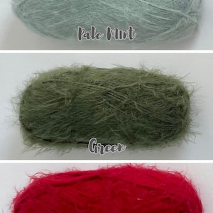 Op de afbeelding: Drie bollen garen in verschillende kleuren: lichtmint, groen en rood. Het garen heeft een zachte, donzige textuur. De kleuren zijn gelabeld met handgeschreven tekst: "Pale Mint", "Green" en "Red".