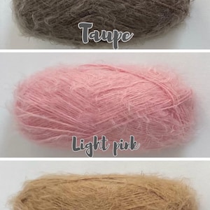 Op de afbeelding: Drie bollen garen in verschillende kleuren. De bovenste bol is taupe, de middelste bol is lichtroze en de onderste bol is kameelbeige. De namen van de kleuren staan onder elke bol garen.