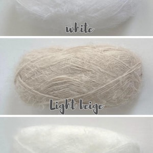 Op de afbeelding: Drie bollen garen in wit, lichtbeige en ivoor. Het woord "white" staat onder de bovenste bol. De middelste bol is gelabeld met "Light beige". De onderste bol is gelabeld met "ivory".