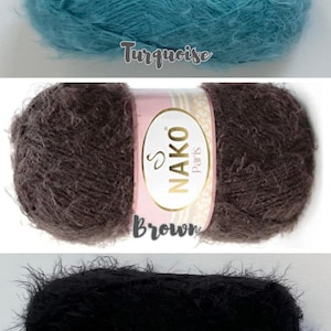 Op de afbeelding: Drie bollen zacht garen in turquoise, bruin en zwart. Het turquoise garen is gemarkeerd met "Turquoise". Het bruine garen heeft een label met "NAKO Paris Brown". Het zwarte garen is gemarkeerd met "Black".