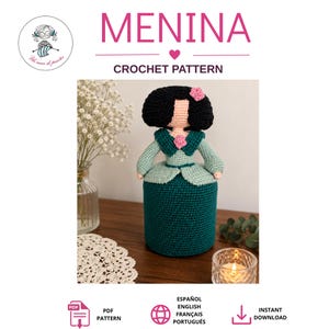 Puede incluir: Un patrón de ganchillo para muñeca titulado MENINA que muestra una muñeca con cabello negro, una flor rosa, una blusa de cuello color verde azulado y una falda verde azulado oscuro. El documento digital incluye instrucciones en español, inglés, francés y portugués.
