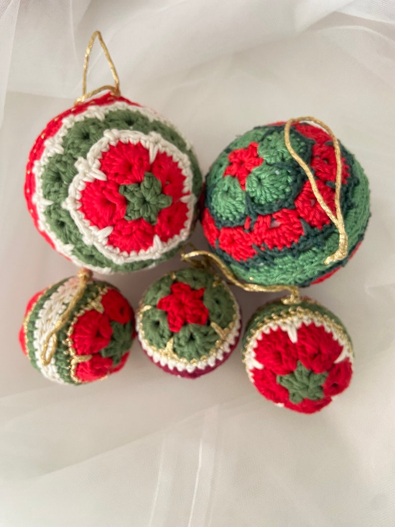 May include: Five crocheted Christmas ornaments in red, green, and white. The ornaments are decorated with a flower pattern.