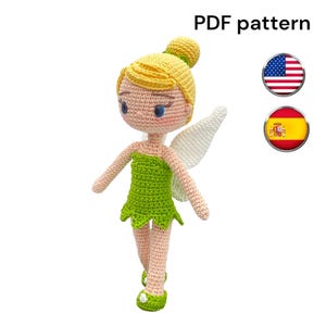 Puede incluir: Una muñeca de ganchillo hecha a mano con un vestido verde, pelo amarillo y alas blancas. La muñeca tiene una expresión dulce y está de pie sobre un fondo blanco. El texto "PDF pattern" es visible.