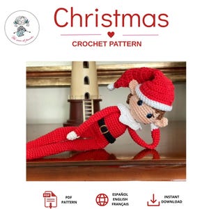 Op de afbeelding: Een gehaakte elfenpop met een rode muts met witte rand, een rood shirt met lange mouwen en een zwarte riem, en een rode broek. De pop heeft een beige gezicht, blauwe ogen en een witte kraag. De tekst "Christmas CROCHET PATTERN" staat erboven.