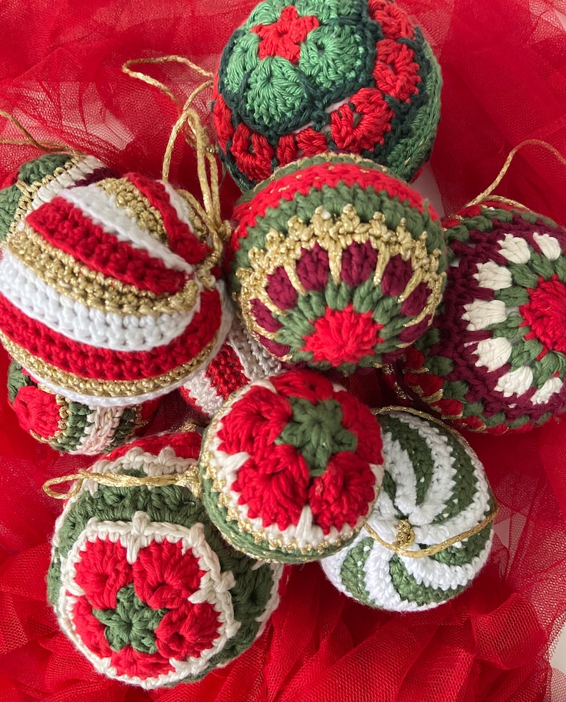 May include: A collection of eight crocheted Christmas ornaments in red, green, white, and gold. The ornaments are decorated with various patterns, including stripes, snowflakes, and flowers.
