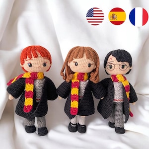 Puede incluir: Tres muñecos de ganchillo hechos a mano, cada uno representando a un personaje de una popular serie de fantasía. Los muñecos tienen pelo rojo, castaño y negro, y visten túnicas negras, camisas grises y bufandas a rayas rojas y doradas.