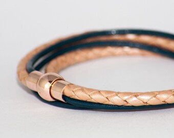 May include: A braided leather bracelet with a rose gold clasp. The bracelet is made of two different colors of leather, one light brown and one dark blue.
