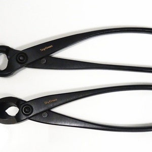 Może przedstawiać: Dwie czarne sekatory z złotym napisem "Tiny Green".