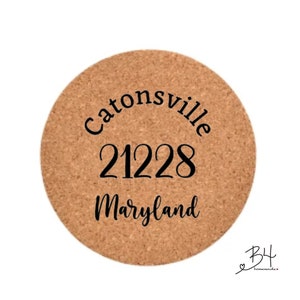 Op de afbeelding: Een ronde kurken onderzetter met de tekst "Catonsville 21228 Maryland" in zwart gedrukt.