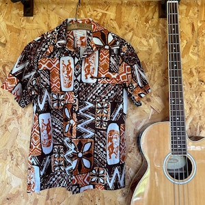 May include: A brown and orange short-sleeved shirt with a geometric pattern. The shirt has a white collar and a button-up front. The pattern features a repeating design of stylized figures and flowers.