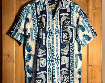 May include: Short-sleeved button-down shirt with a vibrant tropical pattern. The shirt features a white base with blue and teal geometric designs, pineapples, and boat motifs. It is made of a lightweight fabric and is hung on a wooden hanger.